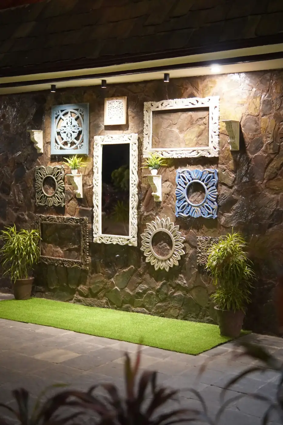 Stone photo wall with carved mirror frames and planters