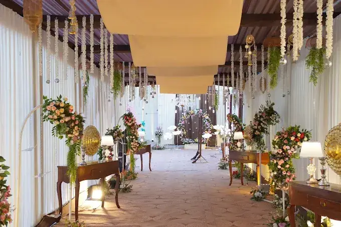 Draped entrance walkway with hanging garlands, lamps and floral consoles