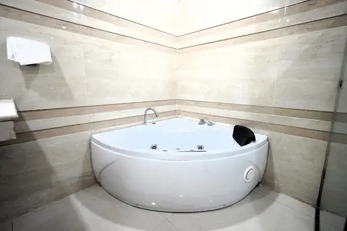 Corner jacuzzi suite bathroom in travertine stone